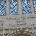 Concrete lettering "Ruane Center for the Humanities" over the door of a brick building with stained glass windows.