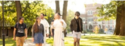 A Dominican Friar walking with students on campus.