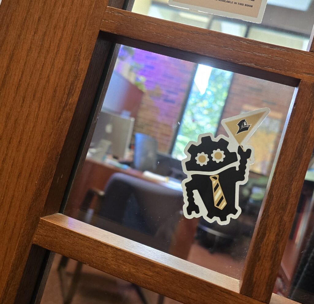 Providence College DubBot sticker on the window of a wooden office door.